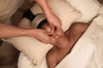 Person entspannt bei einer Gesichtsmassage auf einem Wellnessbett.