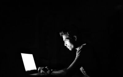 Betrüger sitzt vor seinem Laptop