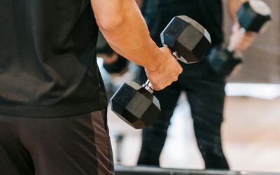Ein Mann, der mit schweren Kurzhanteln vor einem Spiegel trainiert und Fitness sowie Stärke zeigt.