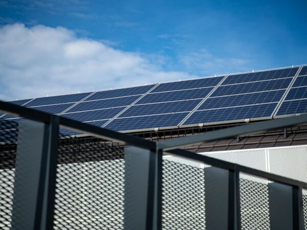 Nahaufnahme moderner Solarpanels auf einem Dach vor einem klaren blauen Himmel, der saubere Energie darstellt.