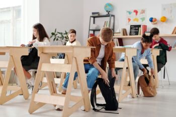 Jugendliche Schüler organisieren Rucksäcke in einem hellen Klassenzimmer.