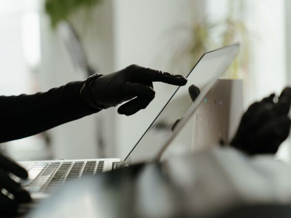 Nahaufnahme einer behandschuhten Hand, die mit einem Laptop in einer eleganten, modernen Büroumgebung interagiert.