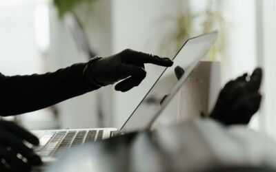 Nahaufnahme einer behandschuhten Hand, die mit einem Laptop in einer eleganten, modernen Büroumgebung interagiert.