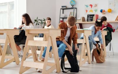Jugendliche Schüler organisieren Rucksäcke in einem hellen Klassenzimmer.