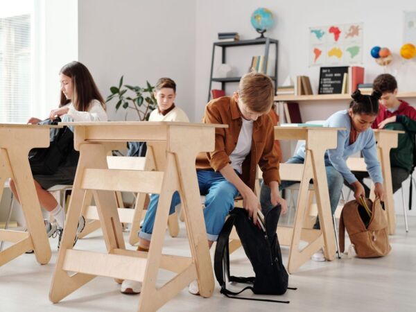 Jugendliche Schüler organisieren Rucksäcke in einem hellen Klassenzimmer.