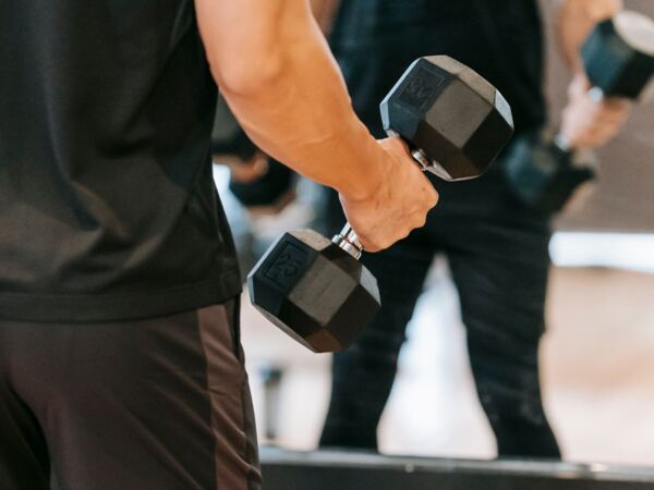 Ein Mann, der mit schweren Kurzhanteln vor einem Spiegel trainiert und Fitness sowie Stärke zeigt.